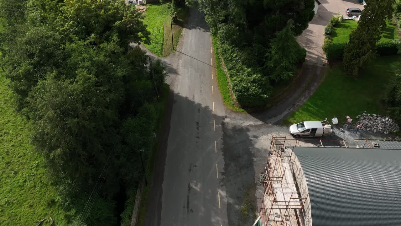 Mullan Village, County Monaghan, Ireland, September 2022. Drone moves fowards tilting up to reveal the heritage village on the main road as a farmers tractor drives past the picturesque houses.
