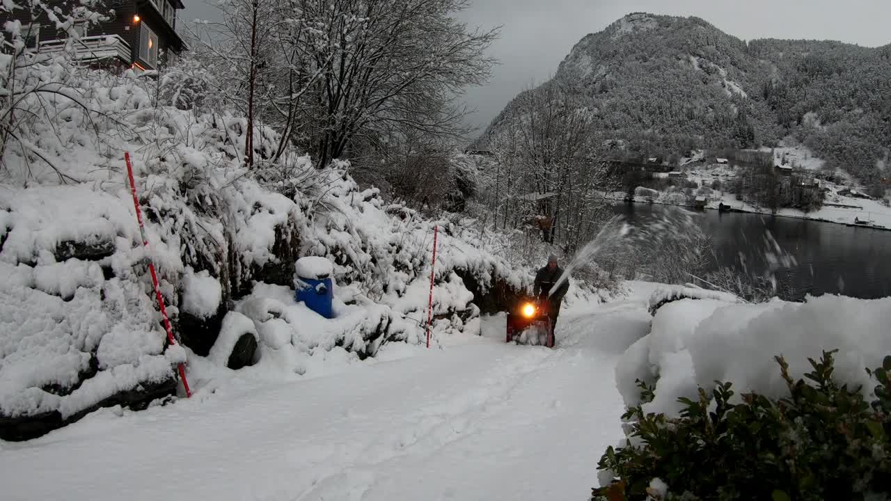 와이드 샷 사람은 눈 덮인 환경에서 도로를 청소하기 위해 빨간 제설기를 사용합니다.