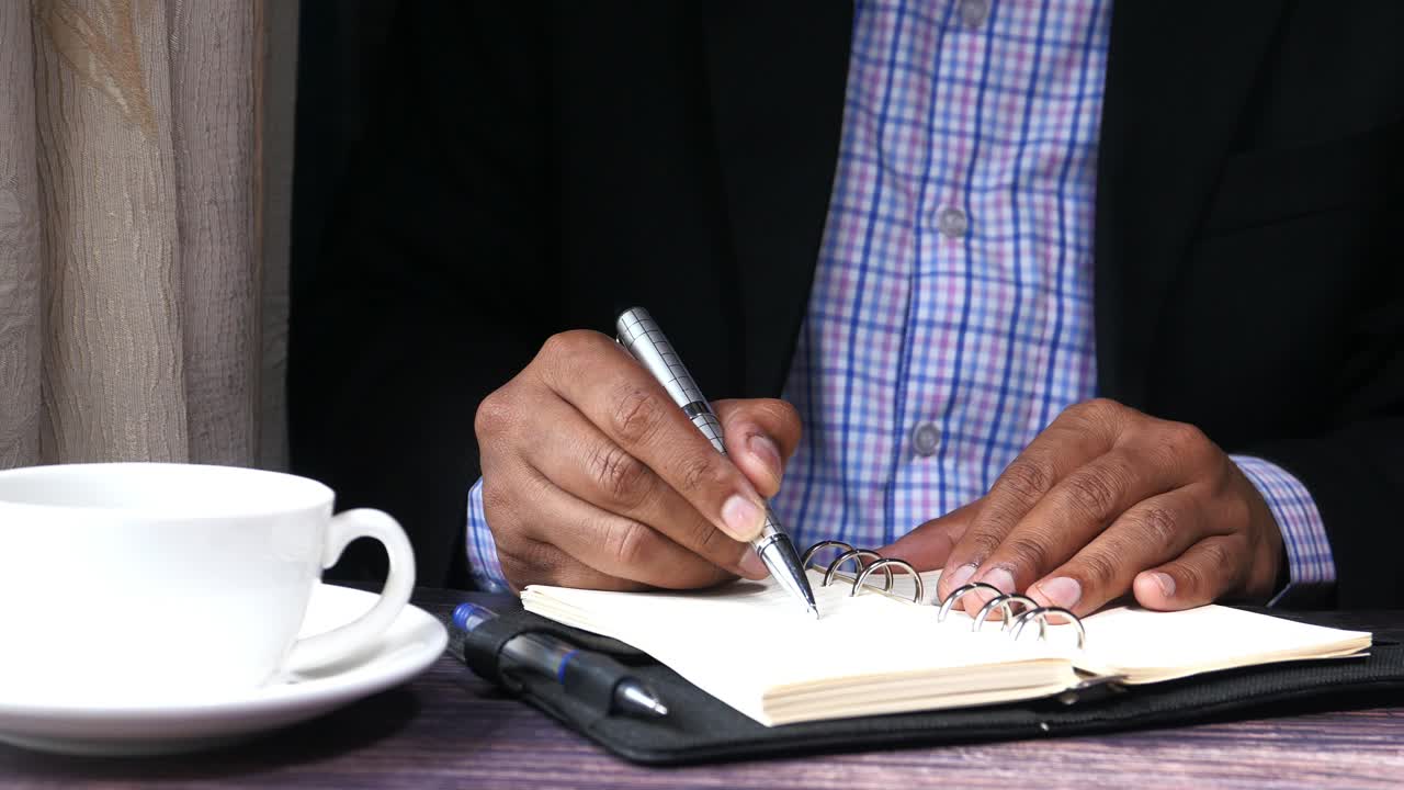 Businessman writing in a notepad with coffee