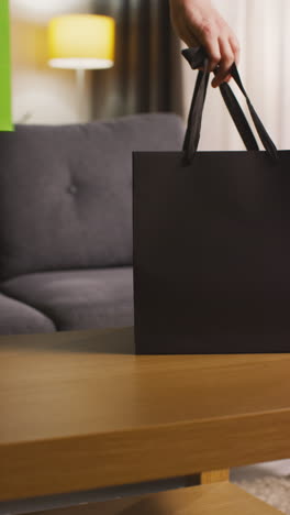 vertical video of person putting presents in gift bags with tags on table in lounge