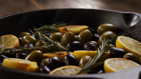 olives, lemon, and herbs in a cast iron pan