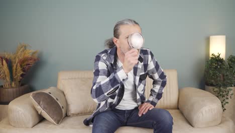 man looking at camera with magnifying glass.