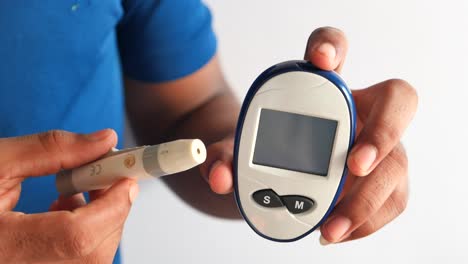 man using a blood glucose meter to test his blood sugar level