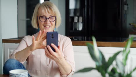 Vista-Frontal-De-Una-Mujer-Mayor-Sonriente-Desplazándose-Por-El-Teléfono.