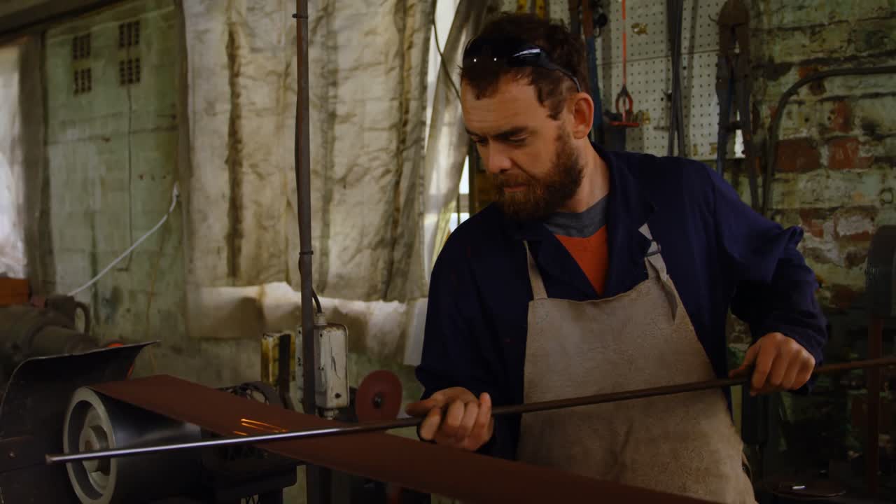 металлург, заточивающий металлический стержень в мастерской 4k