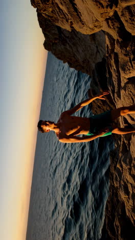 man standing on coastal rocks by the ocean at sunset