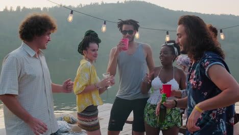 young joyous multiethnic company of friends dancing on pier at lake party