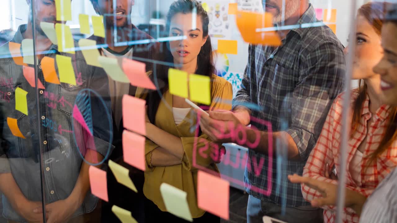 video de creativos diversos colegas masculinos y femeninos escribiendo en notas de memoria en la oficina moderna