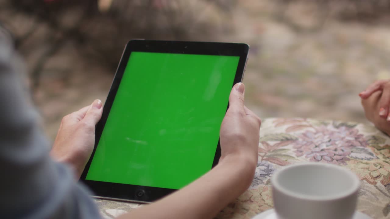 소녀는 야외 커피에서 초상화 모드에서 태블릿을 들고 있습니다.