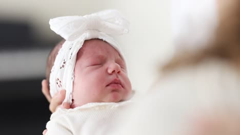 a newborn baby with a white bow sleeping peacefully