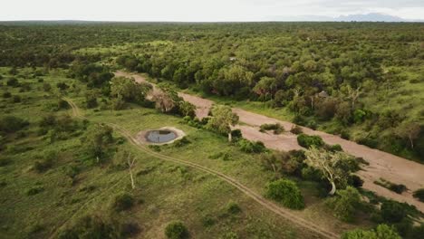 drone shot tilting up from a dry river bed and a dam to show the beautiful african game park landscape with mountains in the background