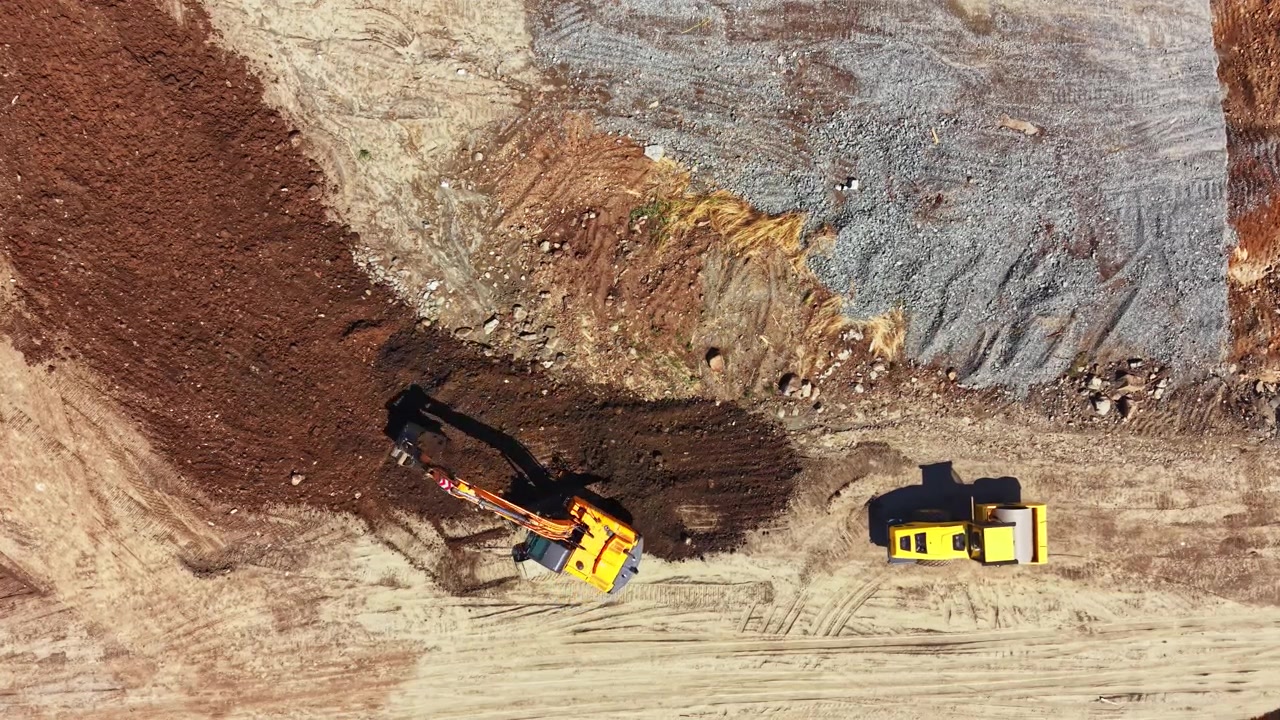 Granite quarry work with excavators and trucks in a large open area during daylight