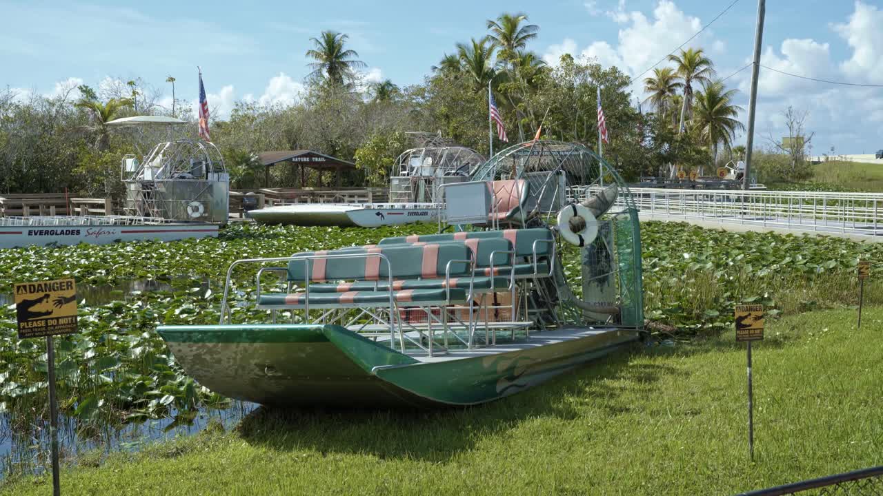 마이애미 (florida) 근처의 에버글레이드 (everglades) 에 정박한 대형 관광 항공 보트의 4k  ⁇ 트와 함께 악어와 악어가 릴리  ⁇   ⁇ 에 숨어 있으며 모두 따뜻하고  ⁇ 은 날에 야자 나무로 둘러싸여 있습니다.