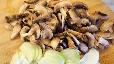 sliced mushrooms and onions on a wooden cutting board