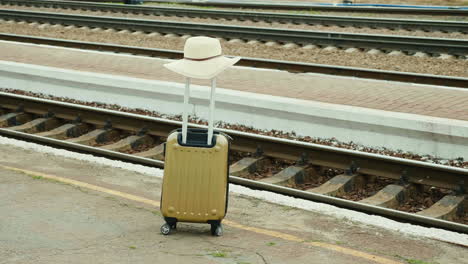 travel bag with a hat on a background of a railroad