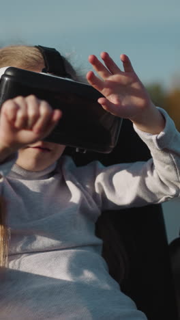 niño con lesión de la médula espinal juega videojuegos usando gafas vr. niña hace movimientos de agarre siguiendo elementos virtuales en el juego en primer plano de fondo borroso