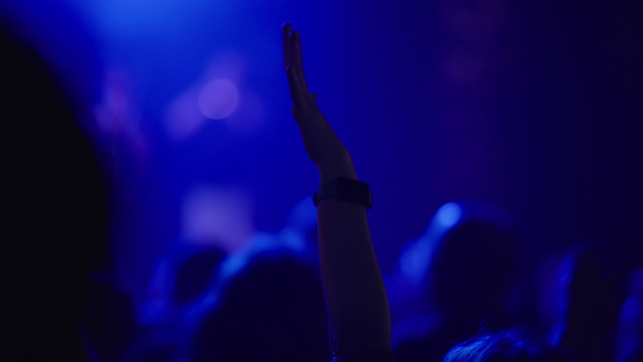Sagome scure della folla a un concerto appena visibili in un bagliore blu intenso
