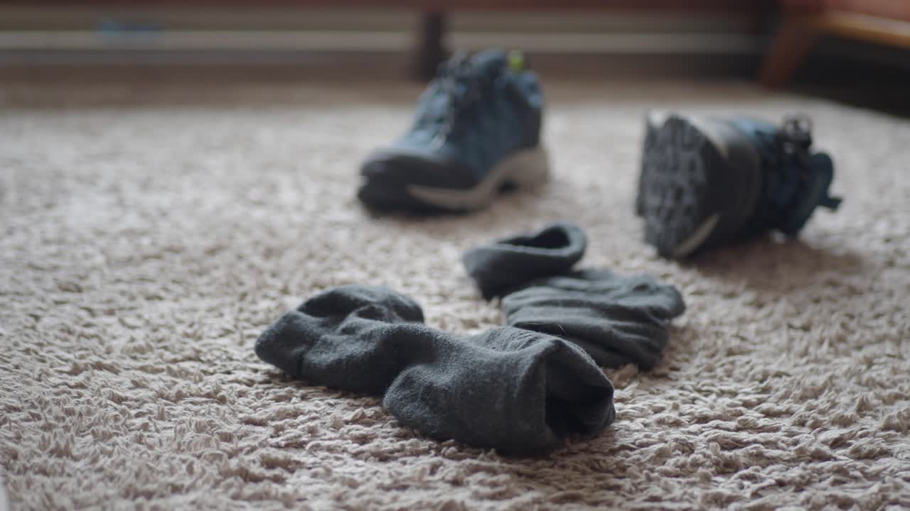 un par de botas de senderismo azules y calcetines negros están en una alfombra beige