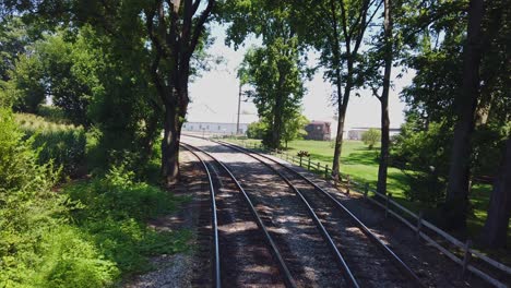 View-From-the-Back-of-a-Train-as-it-Travels-along-Multiple-Tracks-Thru-Countryside-on-a-Sunny-Summer-Day