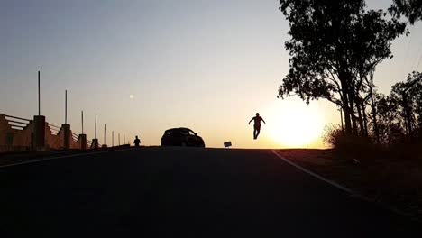 a silhouetted boy running and jumping up during sunset in slow motion