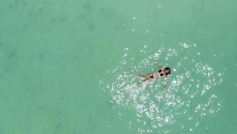 crystal clear turquoise water gently surrounds a tourist floating peacefully on the surface of playa norte, isla mujeres, mexico, enjoying the warm caribbean sun