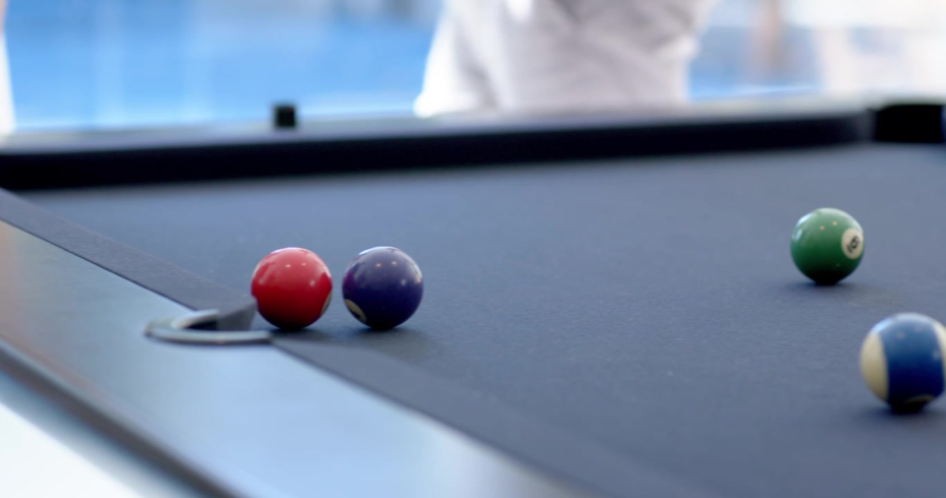 Male is adjusting red ball by corner pocket, lining cue, aiming to sink on blue felt