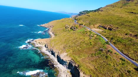 aerial-drone-shot-of-a-Road-on-the-cliff-side-between-the-mountain-and-the-sea