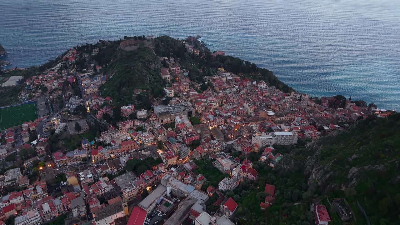 Case residenziali del Comune di Taormina e mare al crepuscolo in Sicilia, Italia - ripresa aerea