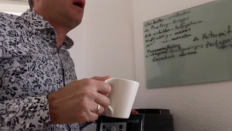 un hombre bebe café de una taza blanca y disfruta del sabor y el aroma