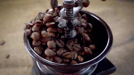 los granos de café caen en el viejo molinillo. cámara lenta con seguimiento de rotación.