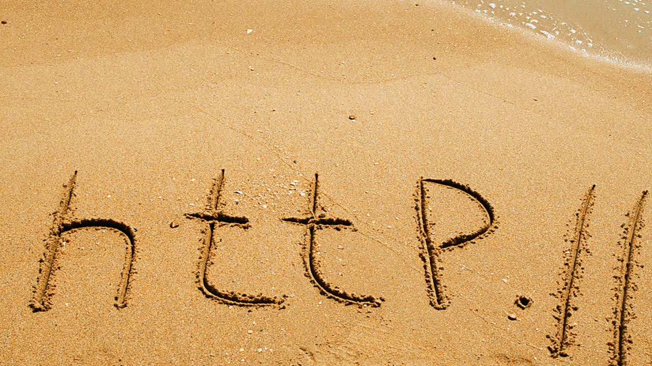 Ordet http håndskrevet i sand på en strand. Optagelse på stranden.