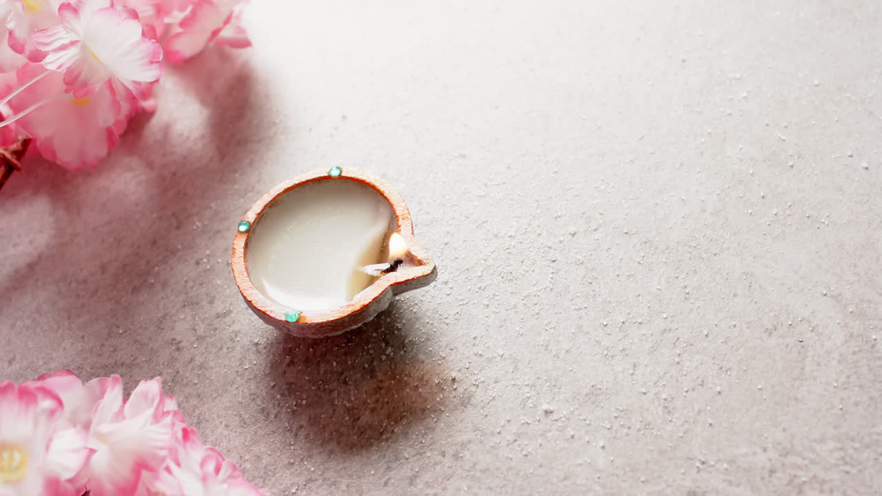 Burning candle celebrating diwali with copy space and flowers on white background