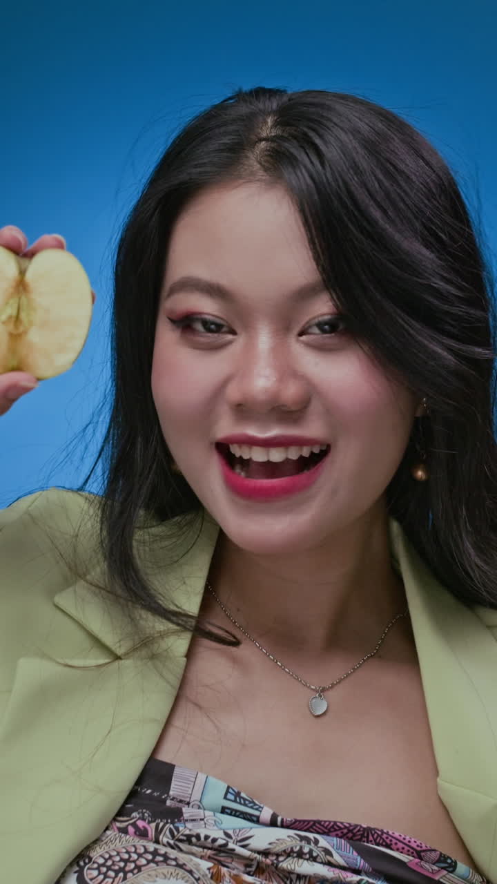 Female Zoomer Interacting with Halves of Apples on Neon Blue Background