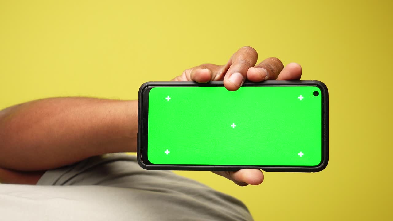 persona sosteniendo un teléfono con una pantalla verde