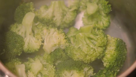 freshly steamed healthy broccoli in pot pan with steam gently rising in slow motion after being cooked ready to serve with main meal as accompaniment side dish 4k