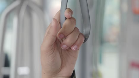 person holding onto a bus handrail