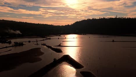 Aerial-view-of-fish-bearing-ponds-captured-during-the-sunset-with-twilight-glazing-on-the-water