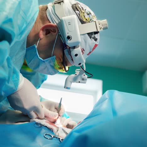 side view of professional doctor in surgical flashlight on head. surgeon doing an operation to a patient using medical tools in the operating room. close-up.