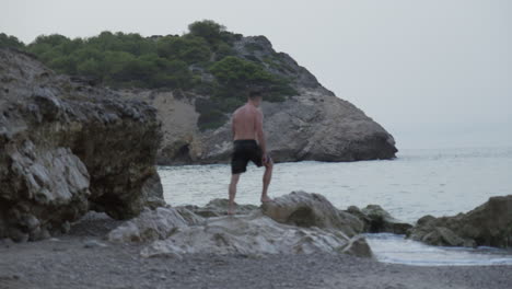 Man-Standing-on-Rock-Near-Sea,-Overlooking-Vast-Ocean-View