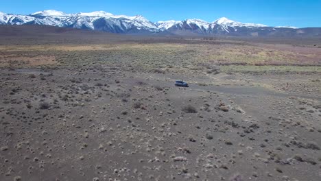 Aerial-above-a-4WD-traveling-on-a-dirt-road-in-the-Mojave-Desert-with-the-Sierra-Nevada-mountains-distant