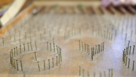 close up on pinball table made of wood. the glass beads roll down on the pinball table. a game played by a child. the subject is on the left.