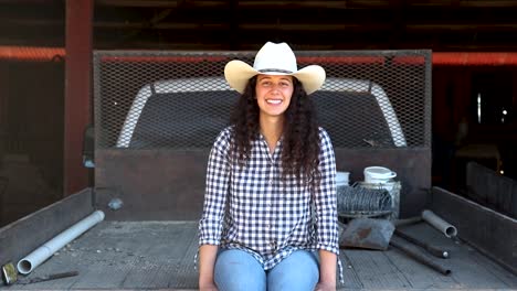 cowgirl smiles at camera in dusty flatbed truck