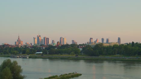 a view across the vistula river of skyscrapers on the western bank, illuminated by the last rays of the setting sun in warsaw