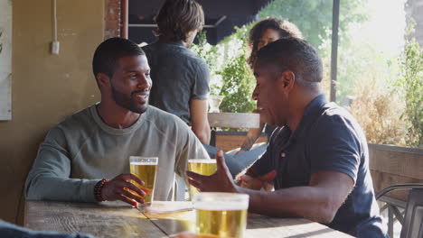 dos amigos se reúnen al aire libre en un bar deportivo disfrutando de una copa antes del juego