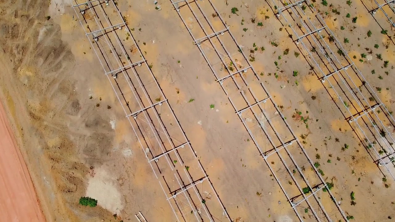 Vast aerial bird's eye view of empty new solar panel frame racks at power plant under construction in Jambur, Gambia with heavy road machinery