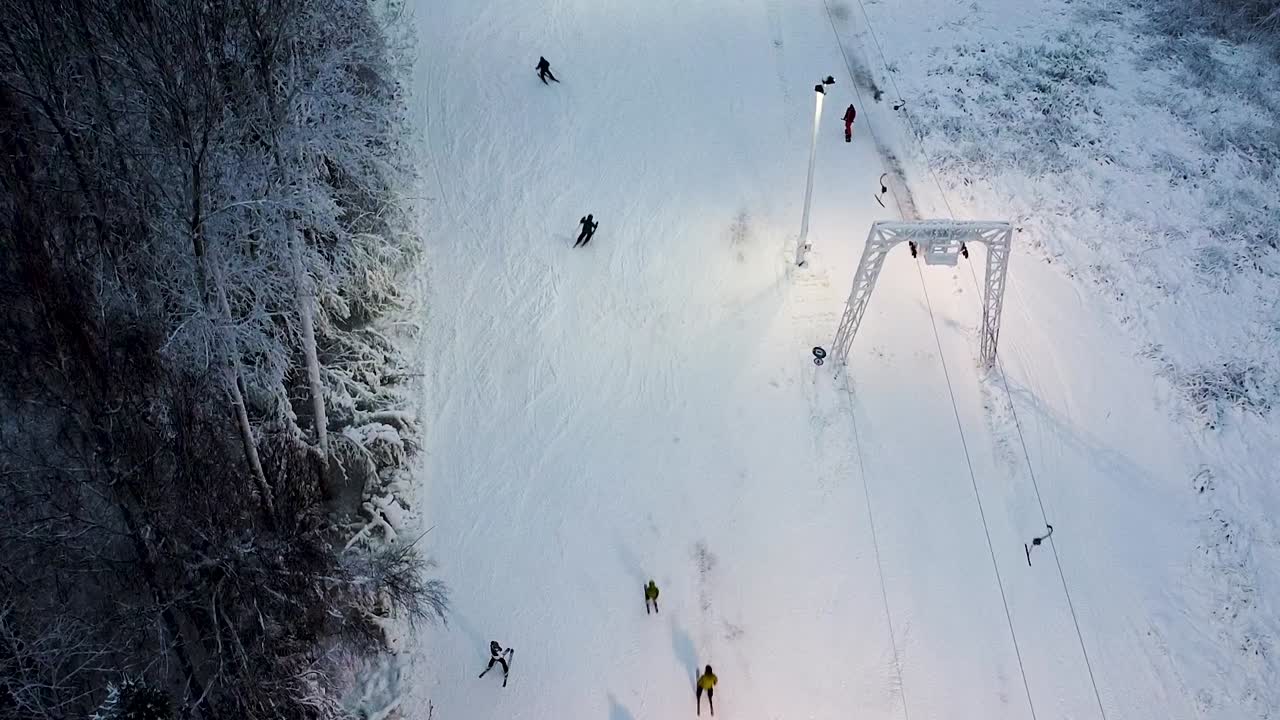 Aerial of mountain skiers descending slowly down a small hill in Estonia