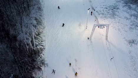 Aerial-of-mountain-skiers-descending-slowly-down-a-small-hill-in-Estonia