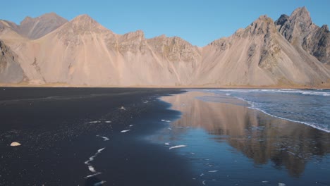 Schwarzer-Sandstrand,-Der-Von-Meereswellen-Unterhalb-Des-Vestrahorn-Bergrückens-Umspült-Wird