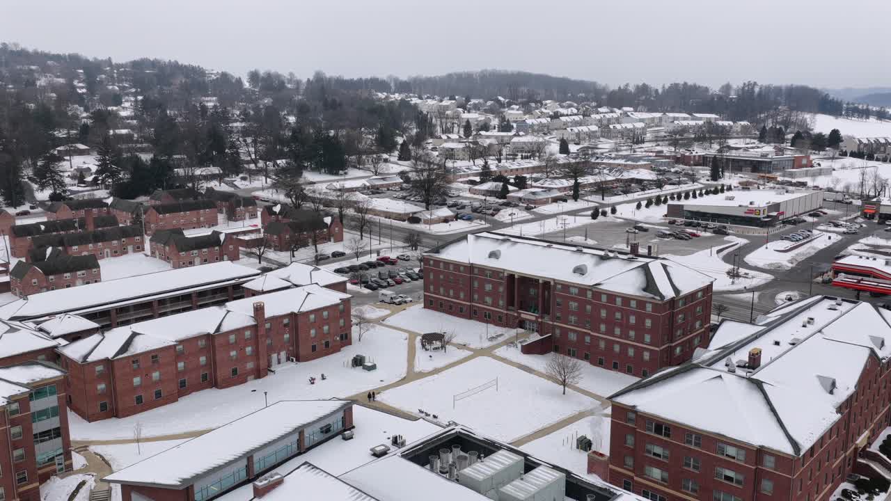 Aerial drone view of York College of Pennsylvania campus in winter, showcasing snow-covered buildings, quiet academic courtyards, and surrounding residential neighborhoods under a calm overcast sky