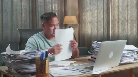 hombre gordo asiático con documentos que explican el trabajo en papel mientras tiene una llamada de video en la computadora portátil en la oficina